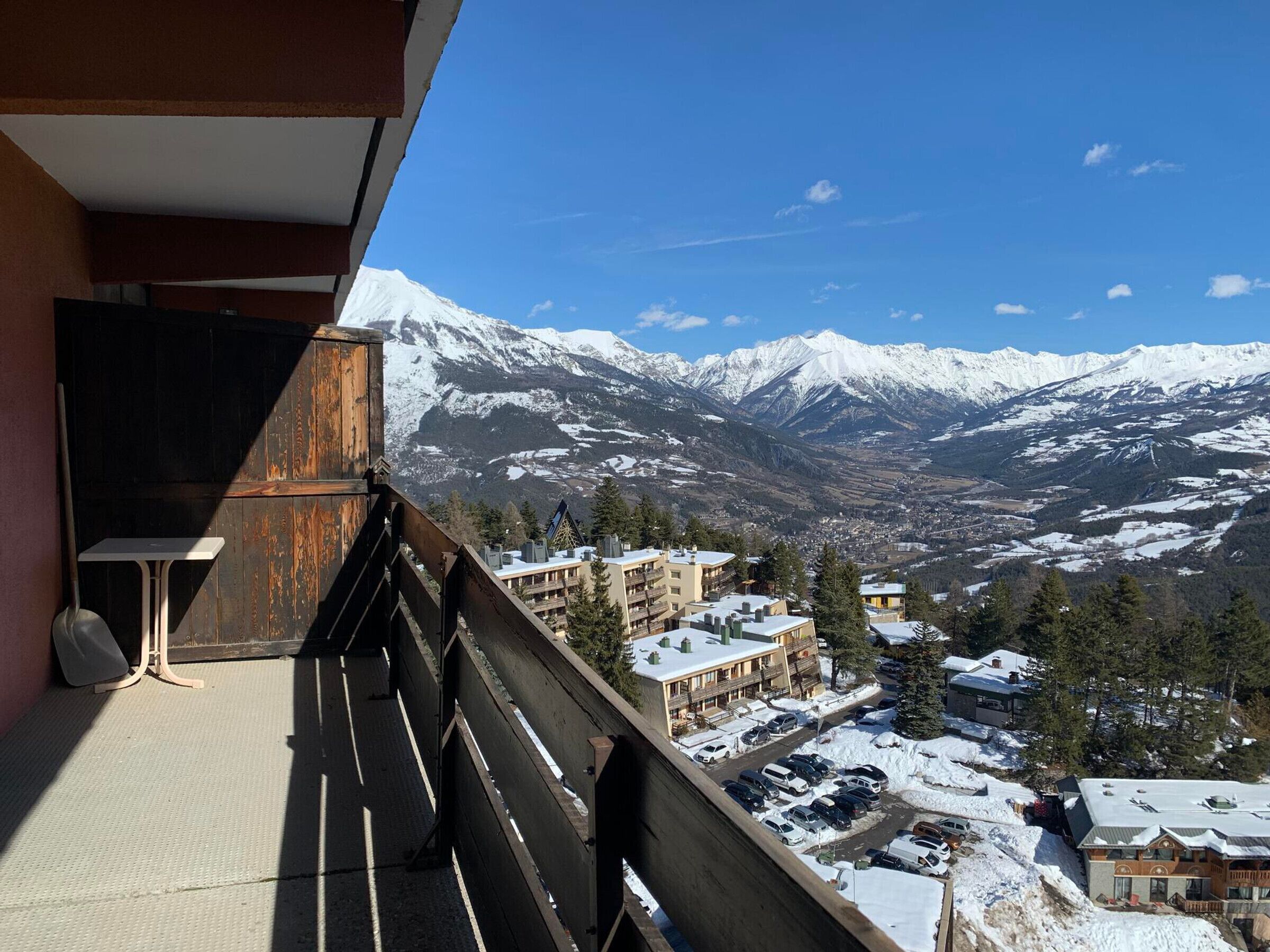 A balcony with a view of snow-covered mountains and a town below.