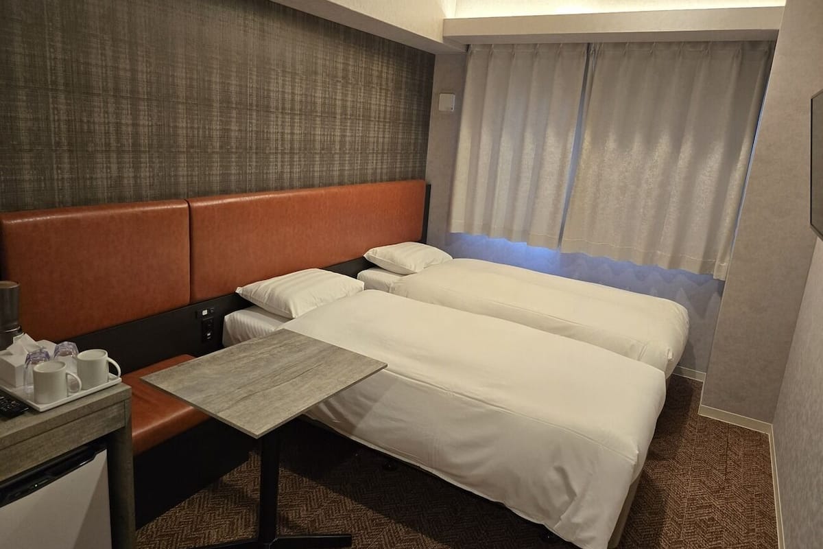 Habitación de hotel con cama, una mesita, un escritorio y una ventana con cortinas.