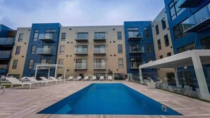 Un bâtiment moderne doté d’une piscine, de nombreux balcons et de chaises longues.
