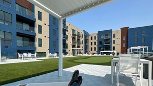 Un espace extérieur aménagé avec des sièges modernes, offrant une vue sur des immeubles à plusieurs étages.