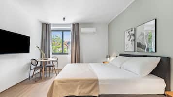 A modern hotel room with a bed, a desk, and a chair.