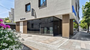 Un edificio moderno con un letrero que dice 'linehome', grandes ventanales de vidrio y un área de entrada pavimentada.