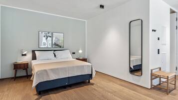 Une chambre à coucher moderne avec un lit, des tables de chevet, un miroir et des œuvres d’art accrochées au mur.