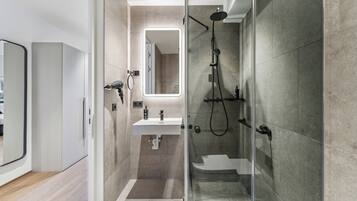 A modern bathroom with a glass-enclosed shower, a white sink, and a large mirror.