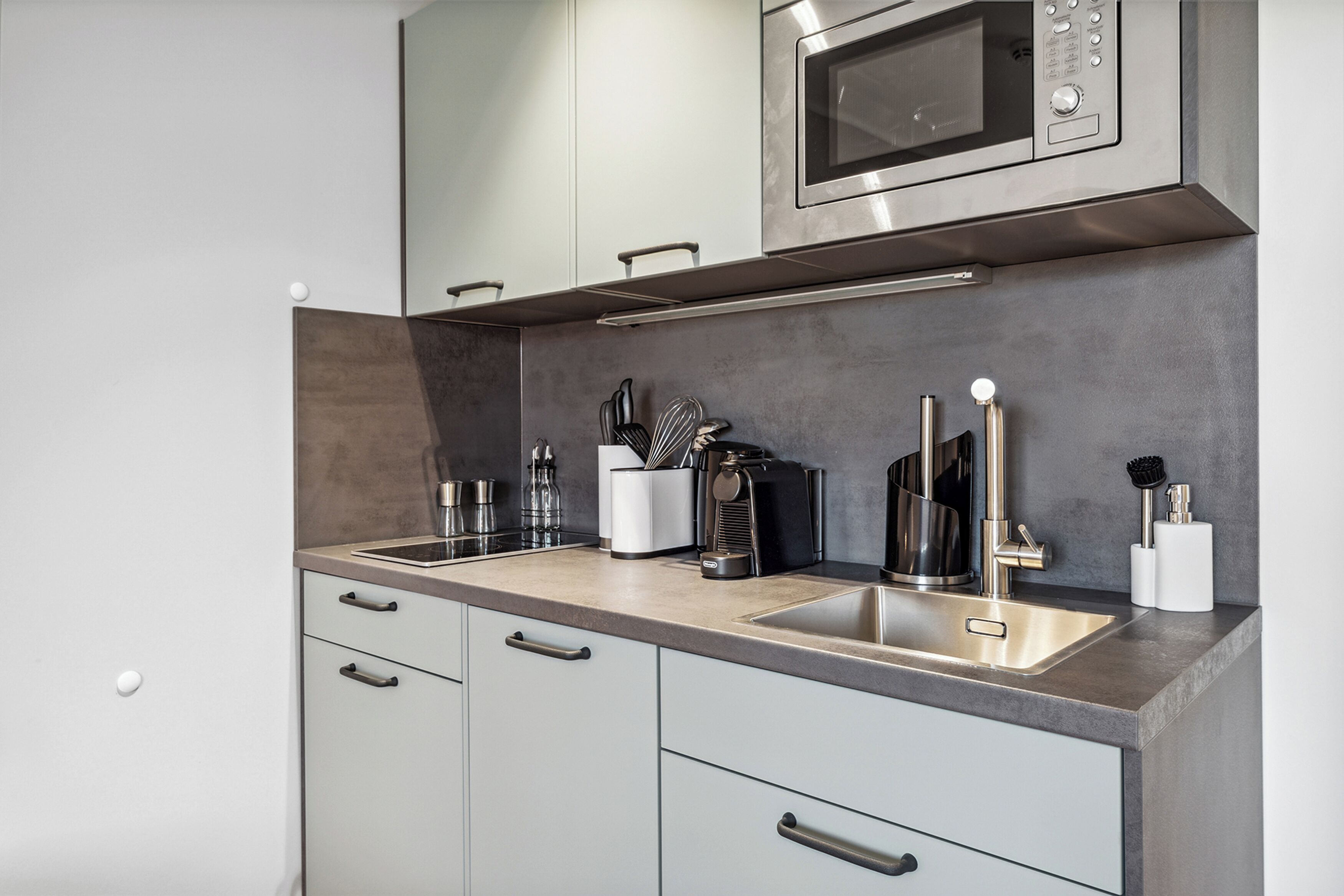 A modern kitchen with stainless steel appliances, a double sink, and a microwave.
