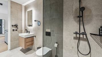 A modern bathroom with a glass-enclosed shower, a white sink, and a wooden vanity.