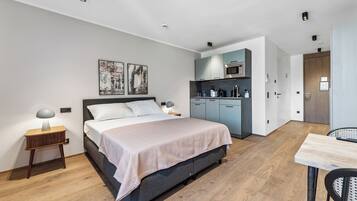 Ein modernes Schlafzimmer mit Bett, Nachttischen, Schreibtisch und einer Küchenzeile.