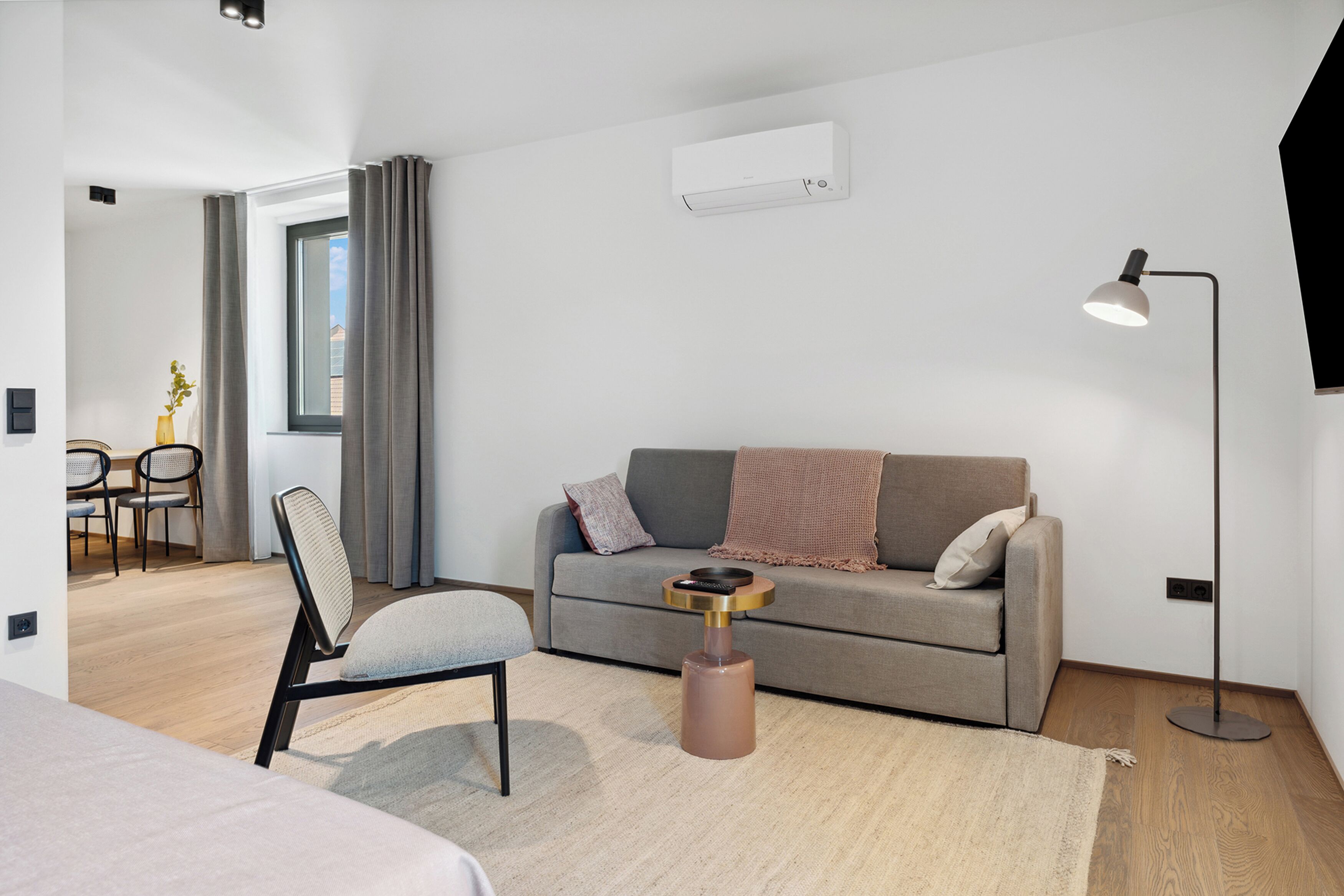 Un salon moderne comprenant un canapé, une table basse, un lampadaire et un coin repas avec des chaises et une table.