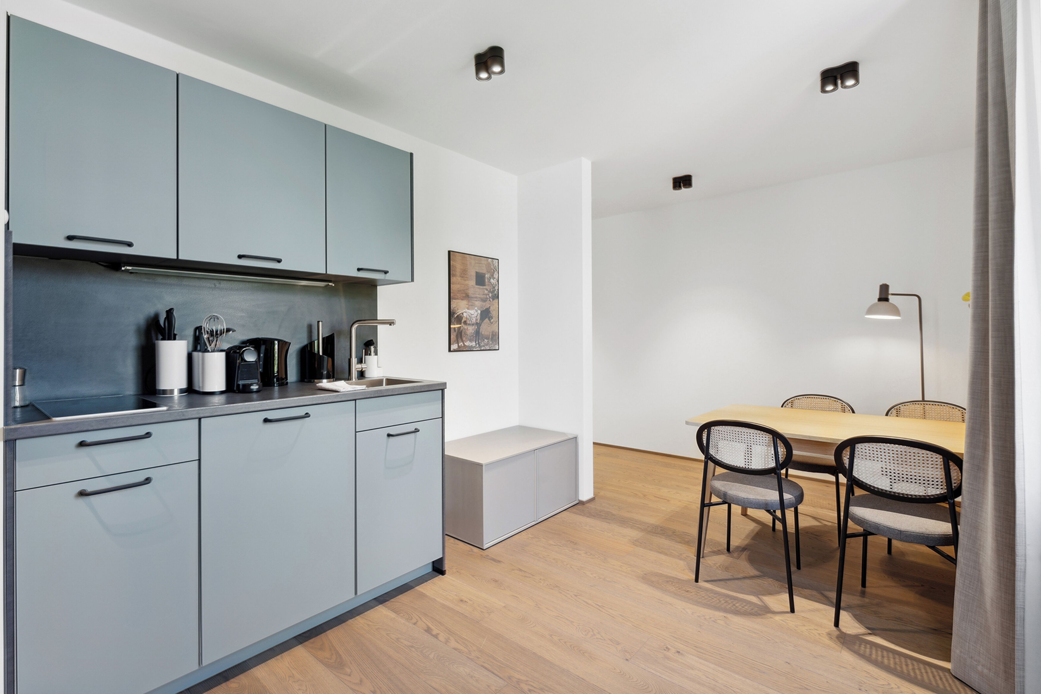 Une cuisine moderne avec des meubles de couleur grise, une table à manger en bois avec quatre chaises et un banc.