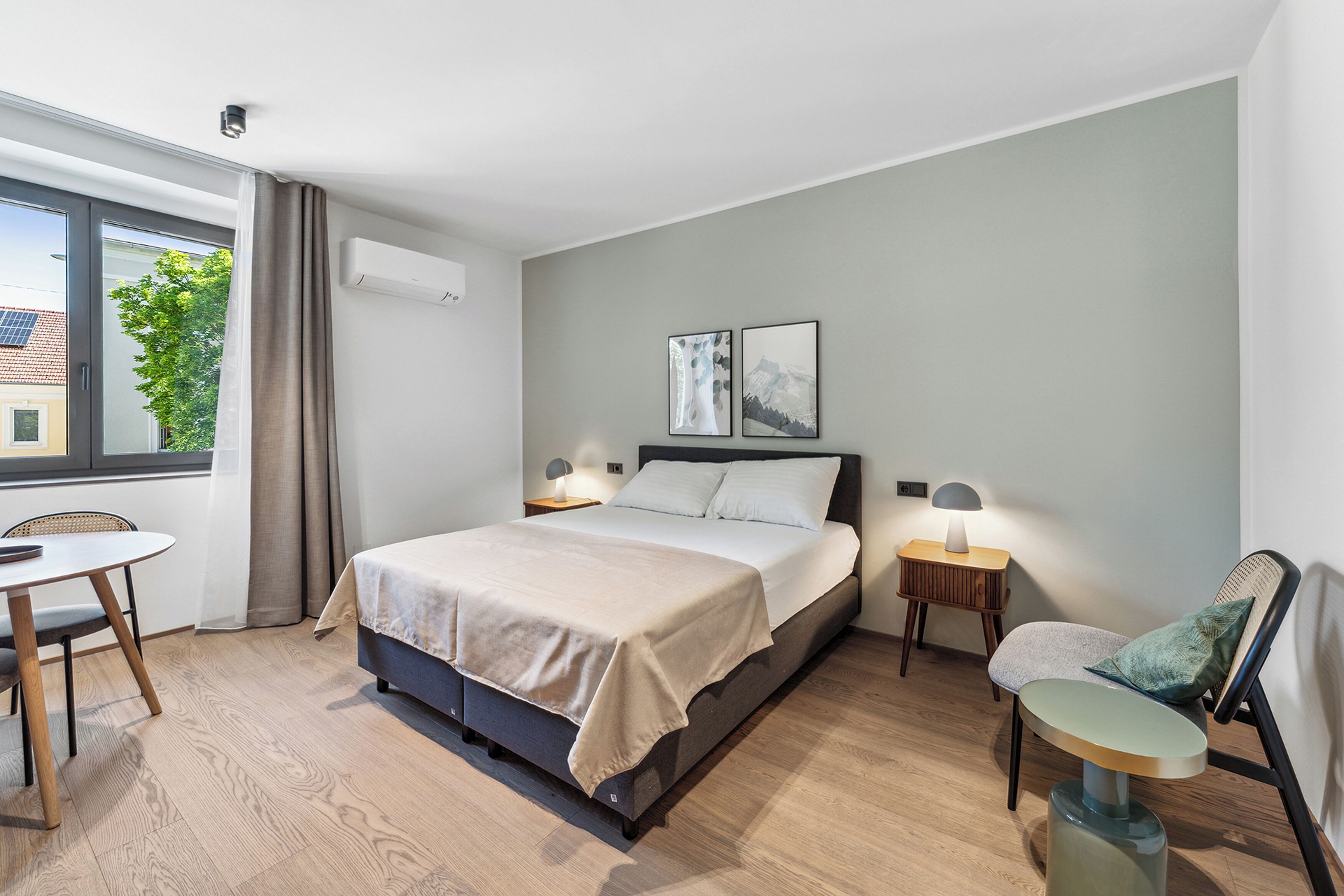A modern hotel room with a bed, bedside tables, a desk, and a chair.