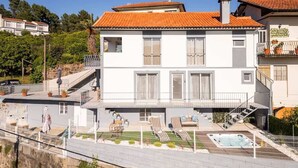 A two-story building with a swimming pool, a balcony with potted plants, and a staircase leading to the upper floor.