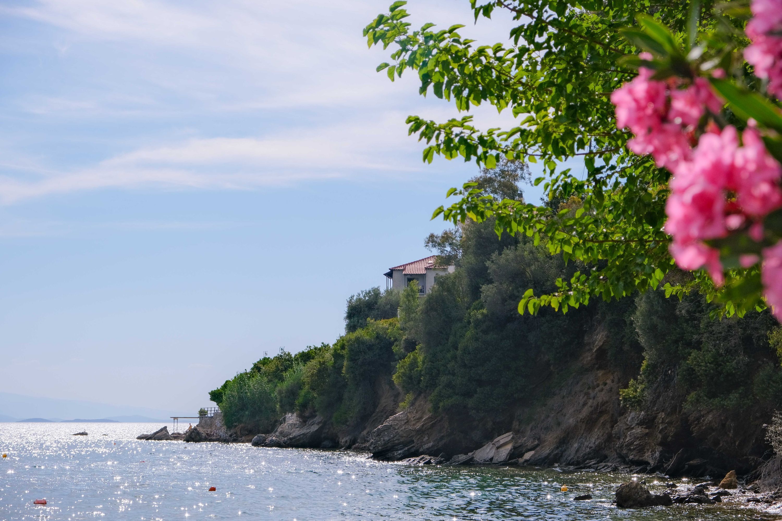 A coastal scene with a house on a cliff overlooking the sea.