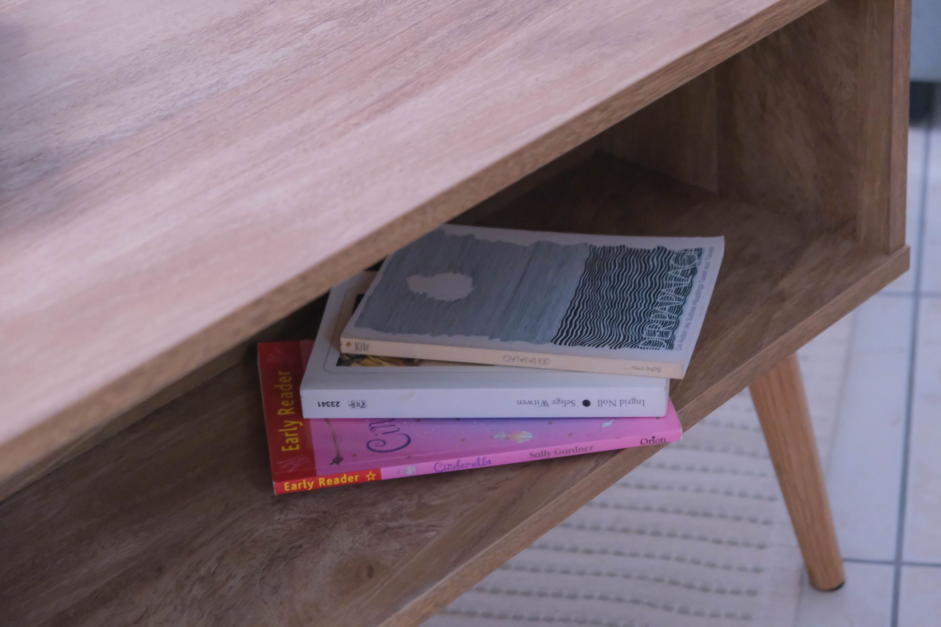 A wooden desk with a shelf holding books.