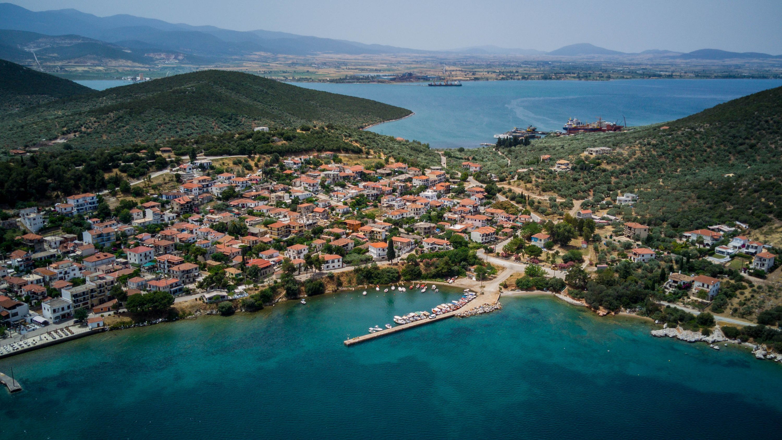 Vue aérienne d’une ville côtière avec des habitations densément regroupées, une jetée et une vaste étendue d’eau.