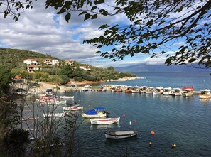 A coastal village with boats docked along the shore, buildings on a hillside, and a clear sky. - Effie's Maisonette With Detached Studio (Almyros)