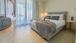 A neatly arranged hotel room with a bed, bedside table, and a window with curtains. - Luaz Suites Volos Center (Volos)