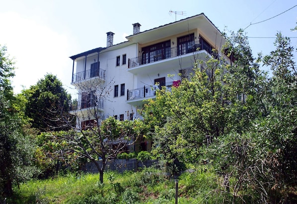 A two-story building with balconies, surrounded by greenery. - Paradeisos Flatlet With Garden View (Zagora-Mouresi)