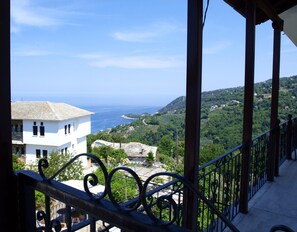 A balcony with a view of a coastal landscape, including a white building and a hill with greenery. - Paradeisos Studio With Garden View (Zagora-Mouresi)