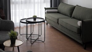 A modern living room with a green sofa, a round coffee table, and a small plant. - Syntagma Mitropoleos Residence (Athens)