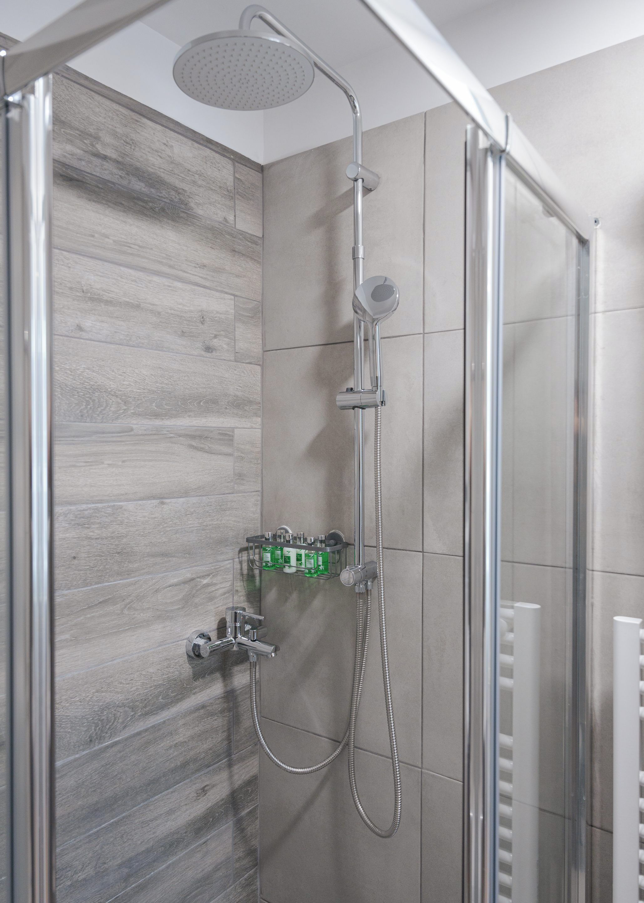 Une douche équipée d’un pommeau de douche à main et d’un robinet mural.