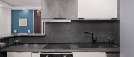 A modern kitchen with dark countertops, a built-in oven, and a dishwasher.