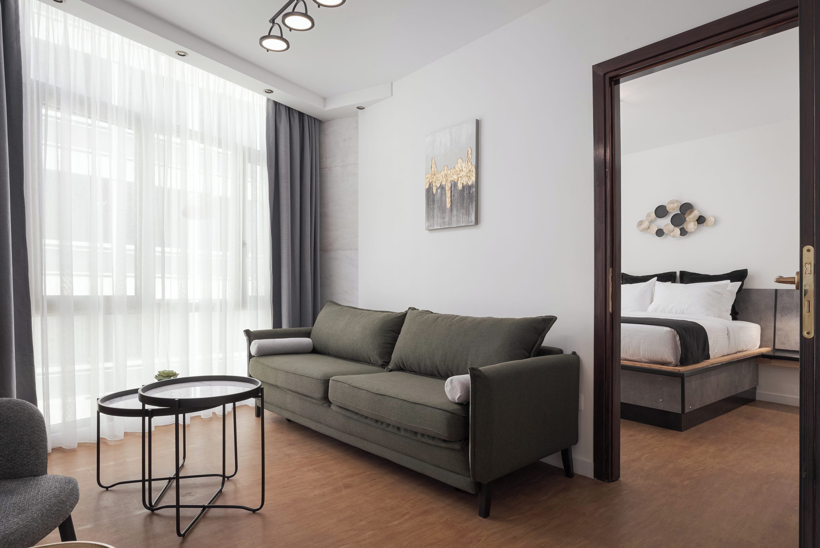Ein modernes Hotelzimmer mit einer Couch, einem kleinen runden Tisch, einem Bett und einem großen Spiegel.