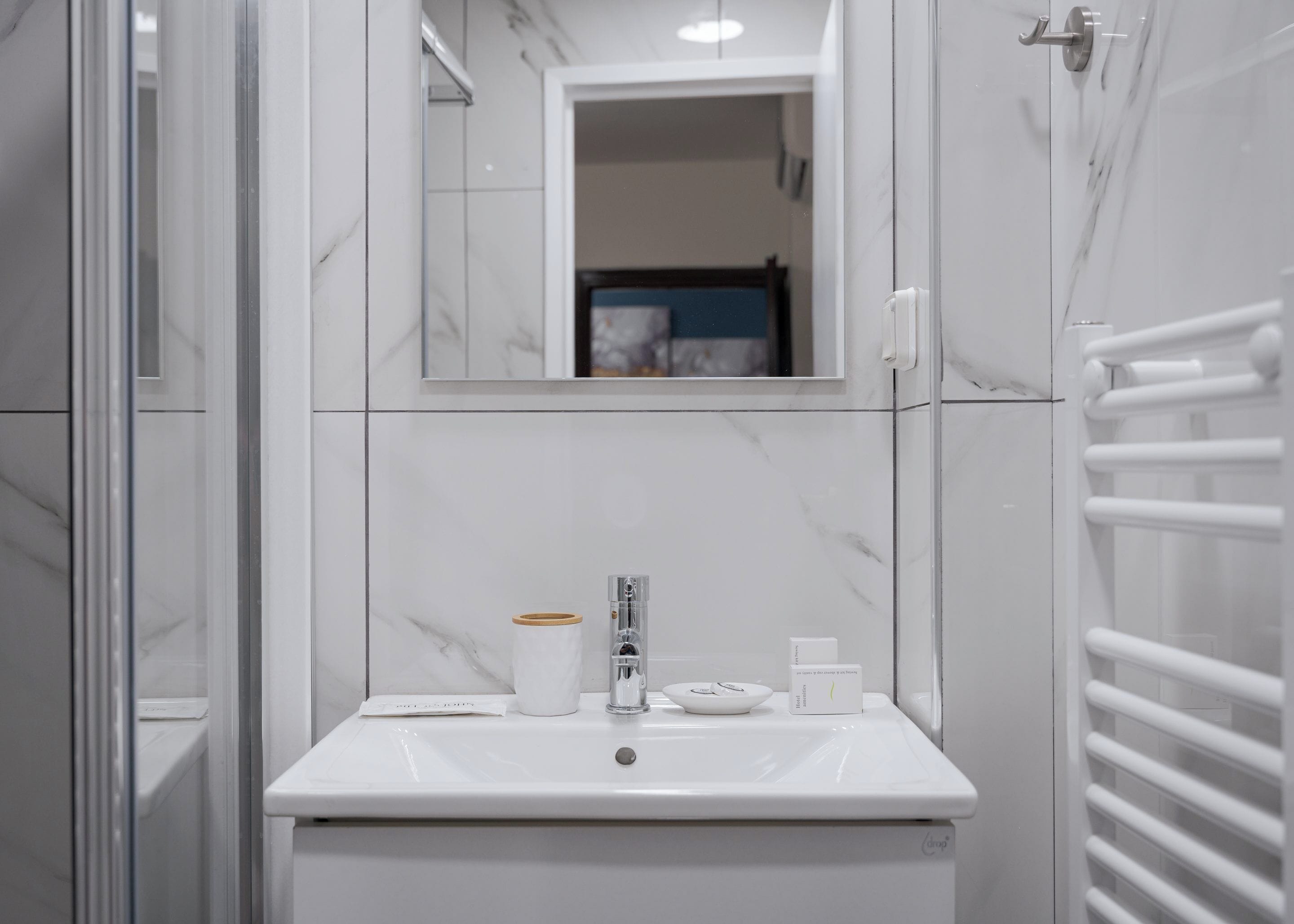 A bathroom with a white sink, a mirror, and a towel rack.