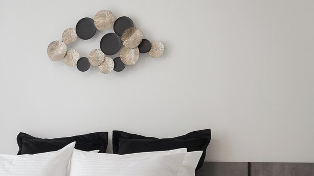 A modern bedroom with a bed, black and white bedding, a wooden headboard, a bedside table with a lamp, and a wall art piece above the bed. - Syntagma Mitropoleos Residence (Athens)
