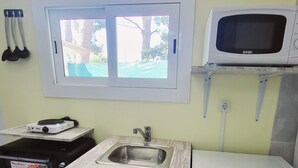Una kitchenette compacta con un lavamanos integrado, un microondas y un refrigerador pequeño.