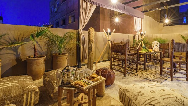 Un espace extérieur aménagé avec des meubles en bois, des plantes en pot et une table dressée avec de la nourriture et des boissons.