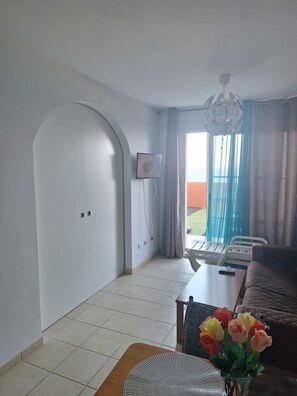 A dining area with a table, chairs, a vase with flowers, and a view of the outdoors. - Oceanic Paradise (Costa Calma)