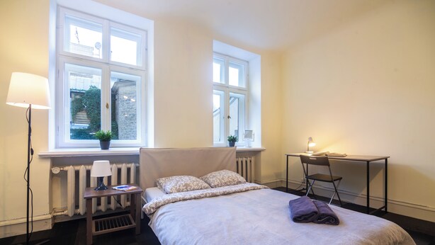 Une chambre bien rangée, avec un lit, des lampes de chevet, une petite table et une chaise.