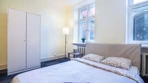 Une chambre d’hôtel avec un lit, une armoire, une fenêtre donnant sur un beau paysage et une lampe.