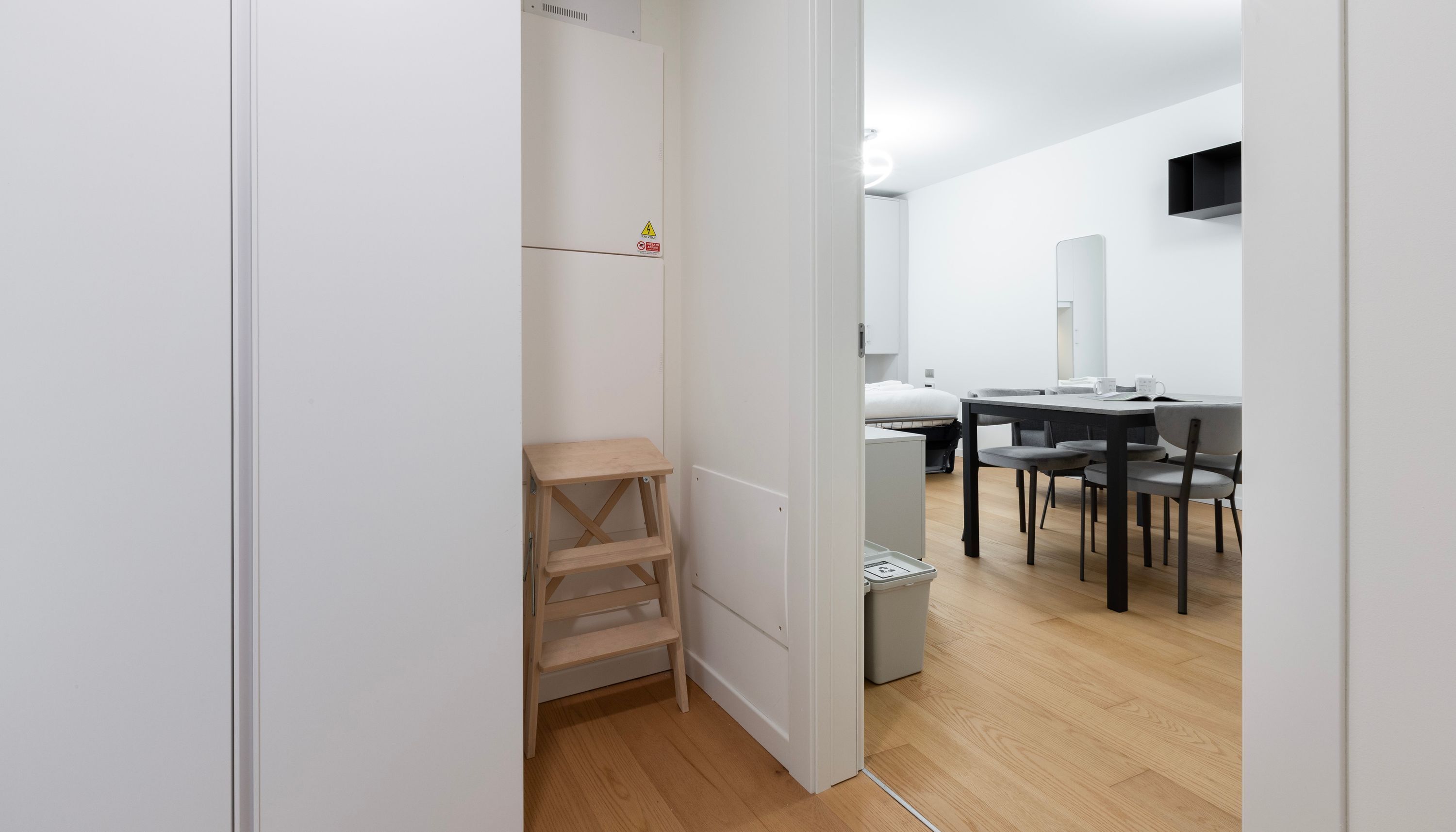 A modern, minimalistic room with a wooden desk, a chair, and a small table.