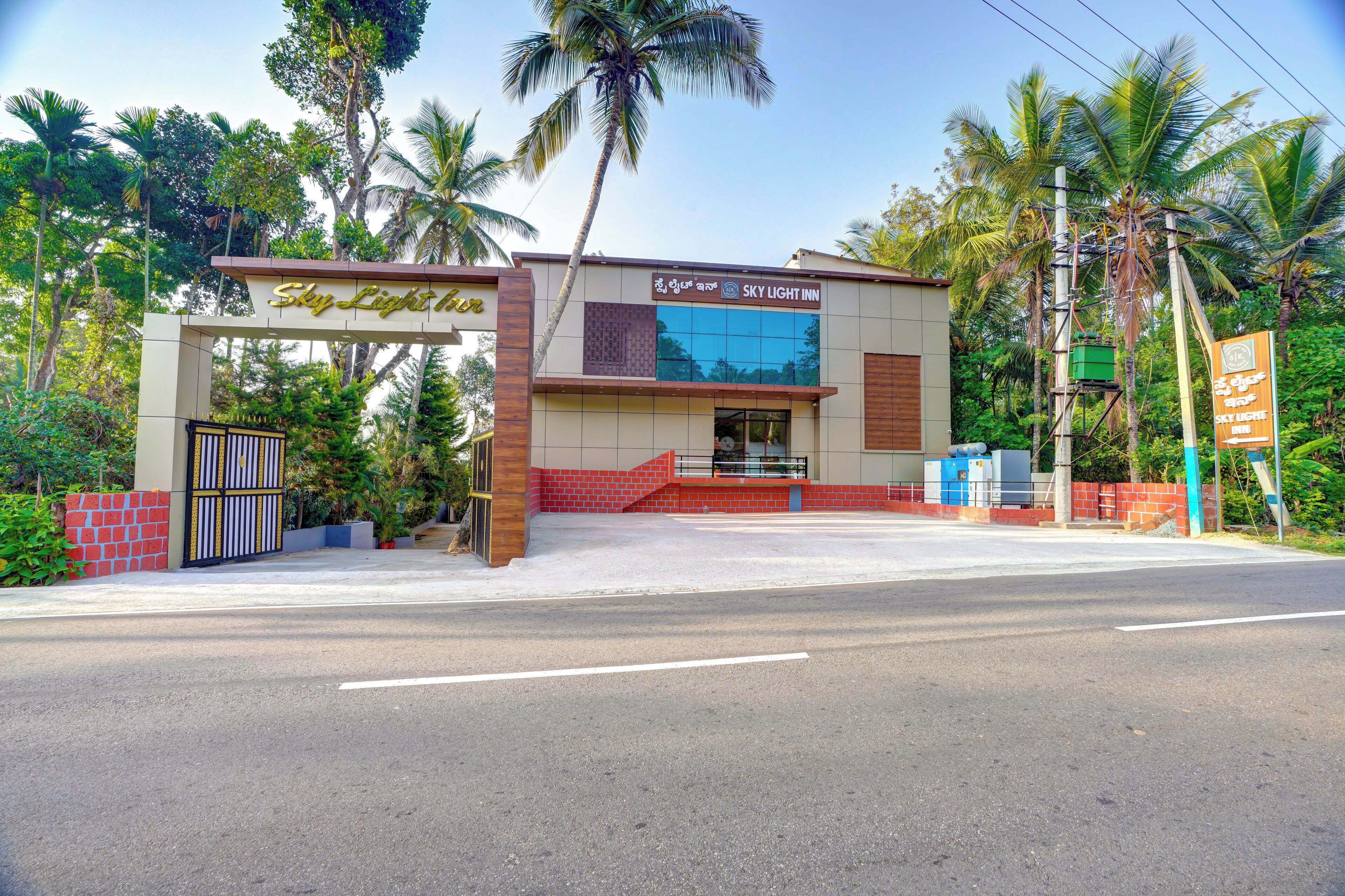 A hotel named 'Sky Light Inn' with a modern facade, a gated entrance, and a red-brick wall.
