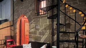 A cozy room with a stone wall, a wooden door, a staircase, and a sofa with cushions. - Rustic 2 Bedroom Stone Apartment in Malonas Rodos (Malonas Rodos)