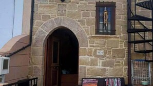 A stone building with a wooden door, a small window, and a metal staircase. - Rustic 2 Bedroom Stone Apartment in Malonas Rodos (Malonas Rodos)