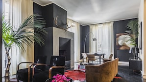 Ein modernes Wohnzimmer mit Kamin, schwarzen und braunen Möbeln und großen Fenstern.
