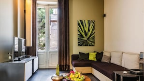 Ein modernes Wohnzimmer mit einer Couch, einem Couchtisch mit Dekoration, einem Fernseher und einem großen Fenster mit Vorhängen.