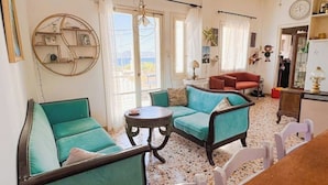 Un salon chaleureux avec des canapés de couleur turquoise, une table basse ronde et un coin repas comprenant une table et des chaises en bois.