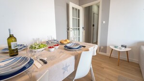 A dining area with a table set for two, featuring a bottle of wine, plates, glasses, and a bowl of salad. - Le Orchidee by Wonderful Italy (Sanremo)