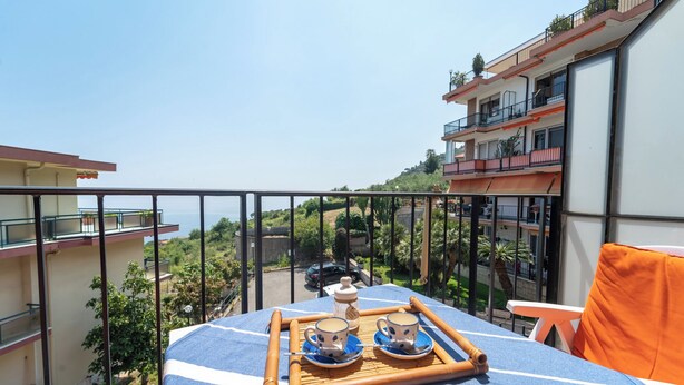 A balcony with a table set for two, overlooking a scenic view of buildings and greenery. - Le Orchidee by Wonderful Italy (Sanremo)