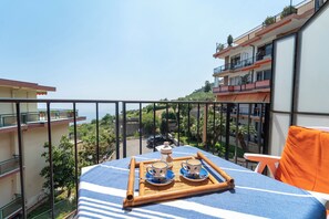 Ein Balkon mit einem für zwei Personen gedecktem Tisch, mit Blick auf eine reizvolle Aussicht auf Gebäude und Grünflächen.