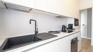 A modern kitchen with a black sink, a coffee machine, and a microwave. - Le Orchidee by Wonderful Italy (Sanremo)
