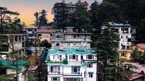 Un immeuble à plusieurs étages doté de balcons, entouré d’arbres et d’autres bâtiments.