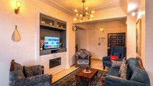 Un salon avec une cheminée, un téléviseur et deux fauteuils.