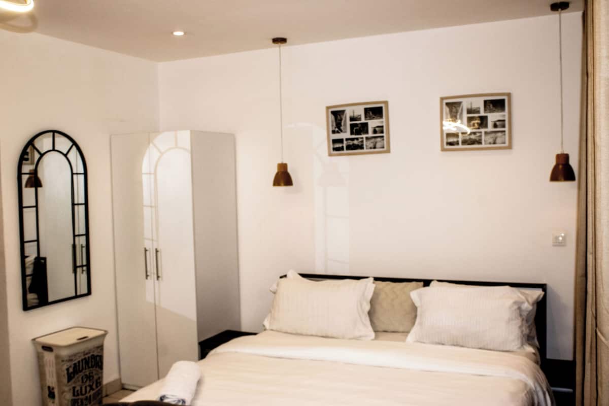 A bedroom with a bed, a wardrobe, a mirror, and two wall-mounted picture frames.