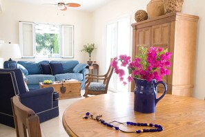 A living room with a blue sofa, wooden coffee table, and a blue vase with pink flowers.