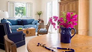 En stue med en blå sofa, et træbord og en vase med lyserøde blomster.