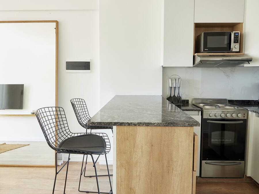 Una cocina moderna con una isla central, horno integrado y microondas.